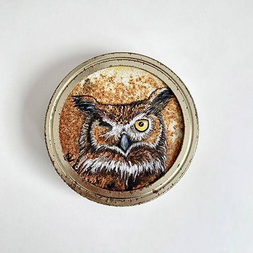 Against a rusty background, a brown and white owl gives a jaunty wink, his open eye a bright yellow.