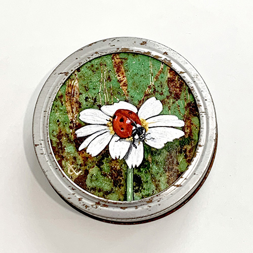 A bright red ladybug sits atop a single white-petaled daisy in the foreground. The background is green and mottled brown of rust. 