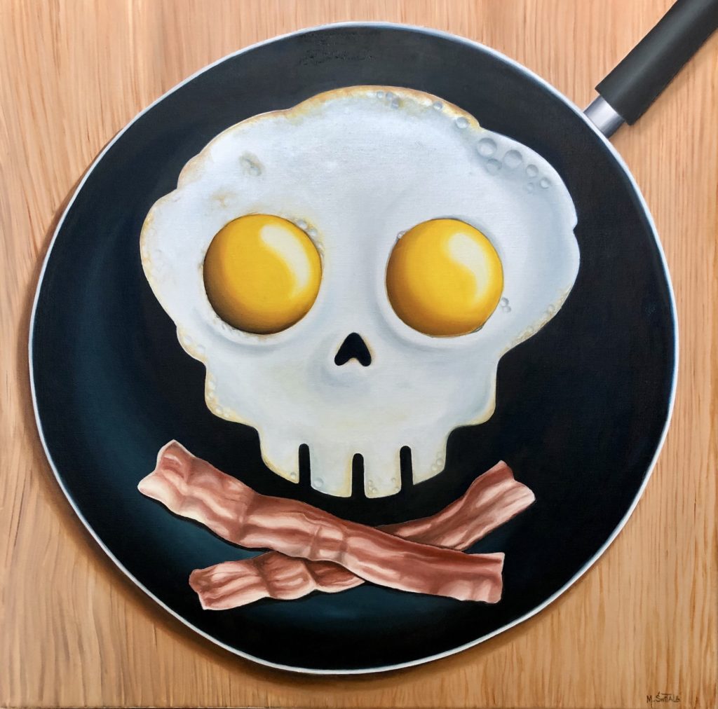 Image description: Surreal painting of a frying pan with bacon and eggs. The black pan sits on a wooden surface. The eggs are shaped like a skull with the yellow yolks as eyes. The bacon is crossed to create an “x” below the skull to look like the classic image of a pirate flag with skull and crossbones.