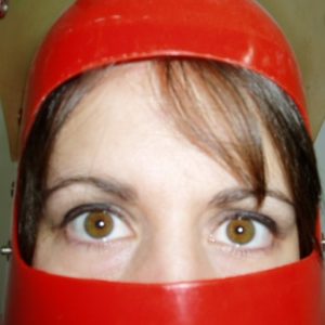 This is a headshot of ERIKA LINCOLN. Erika is a white woman with brown eyes and brown hair. In this image only Erika's eyes and forehand are visible as she is wearing a hard red plastic hat and face covering