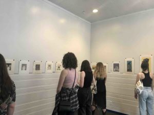This is a photo of five people viewing Kelly Haydon's printwork displayed on the AANM Gallery walls.