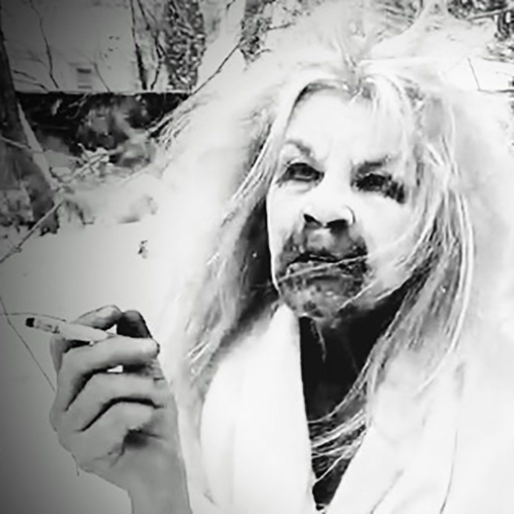 Art Photograph of Susan Aydan Abbott. She has charcoal dripping from her mouth and nose and around her eyes. Her hair is wild and she is wearing a blanket in the snow while smoking a cigarette.