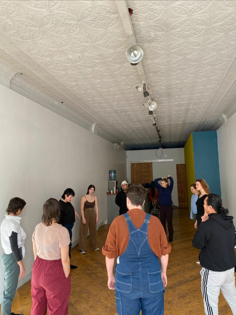 This is a photograph of a 10 people standing in a circle in a blank room