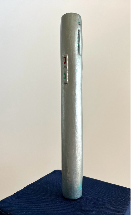  Larger than life, a long silver tube with a slit for the microphone at the top front with a green light over it. On the side is a toggle switch for settings marked in red and green with a clip on the back.